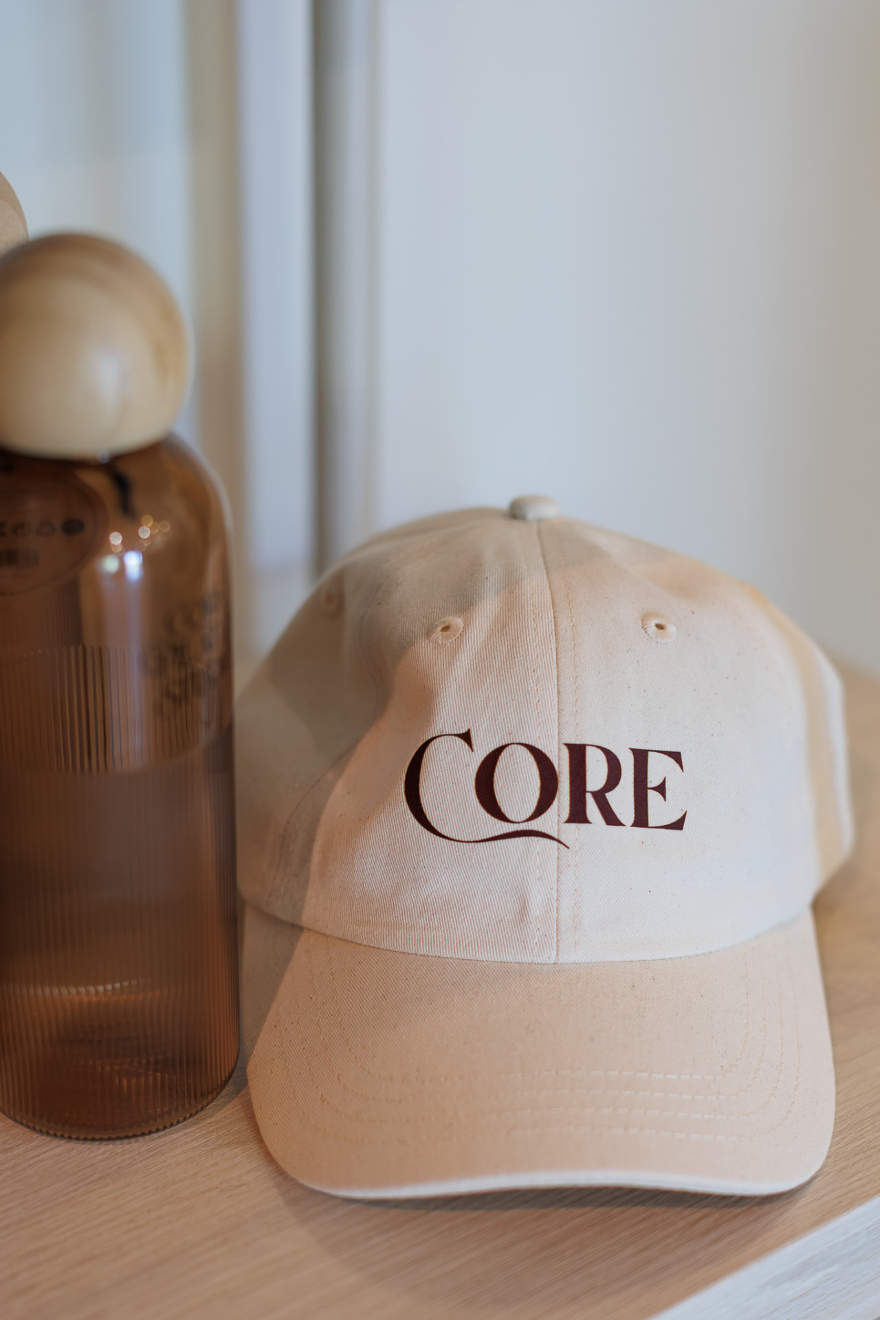 Core Cap i krämljus med CORE på framsidan, på ett ljust underlag
